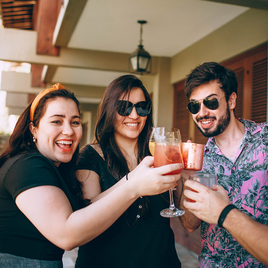 Three people cheering with cocktails